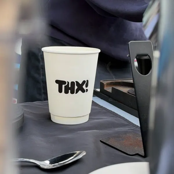 A white thx! cup on a black-draped pop-up table